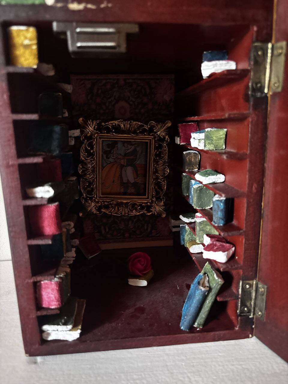 Pequeño cofre en forma de libro que se abre a una biblioteca en miniatura